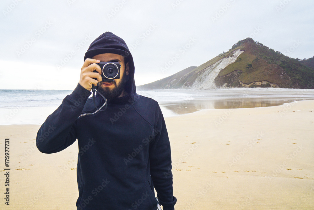 Hooded man taking a photo on the beach Hooded man taking a photo on the beach