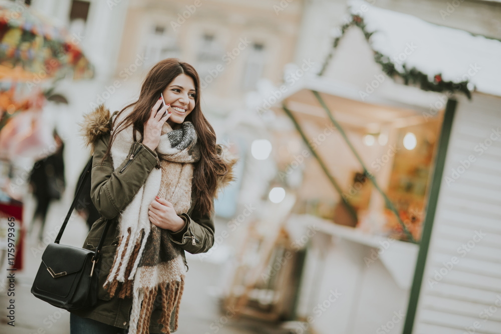 Young woman using phone in park at  cold winter day