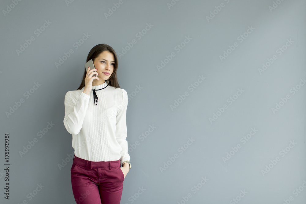 Elegant businesswoman with mobile phone by the wall Elegant businesswoman with mobile phone by the wall