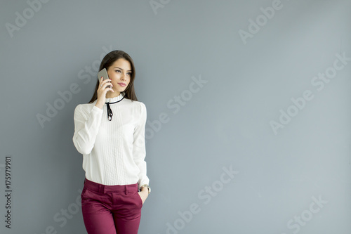 Elegant businesswoman with mobile phone by the wall