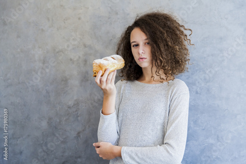 Cure curly hair girl eating croissant