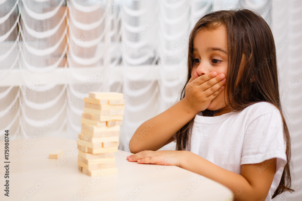 cute little girl excites with wooden block game jenga at home selective focus cute little girl excites with wooden block game jenga at home selective focus