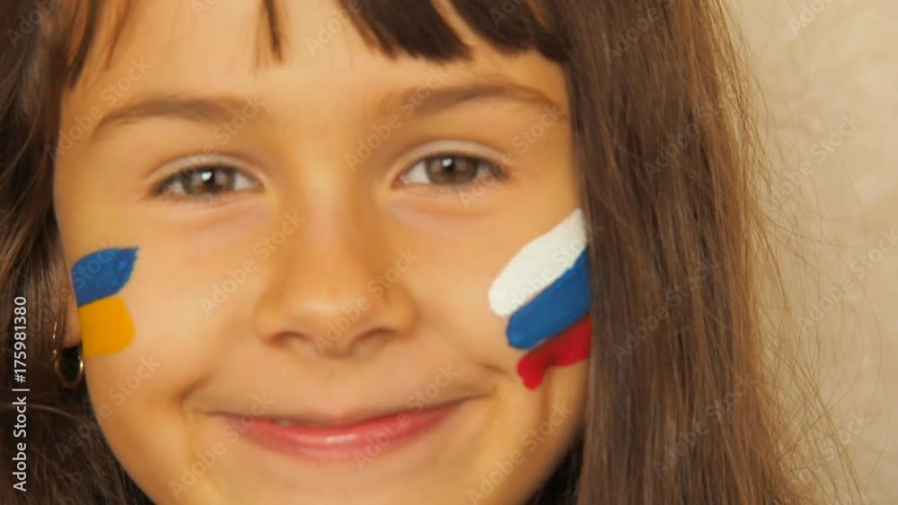 Happy child with the flag of Russia and Ukraine. A little girl with painted flags of Russia and Ukraine. Happy child with the flag of Russia and Ukraine. A little girl with painted flags of Russia and Ukraine.