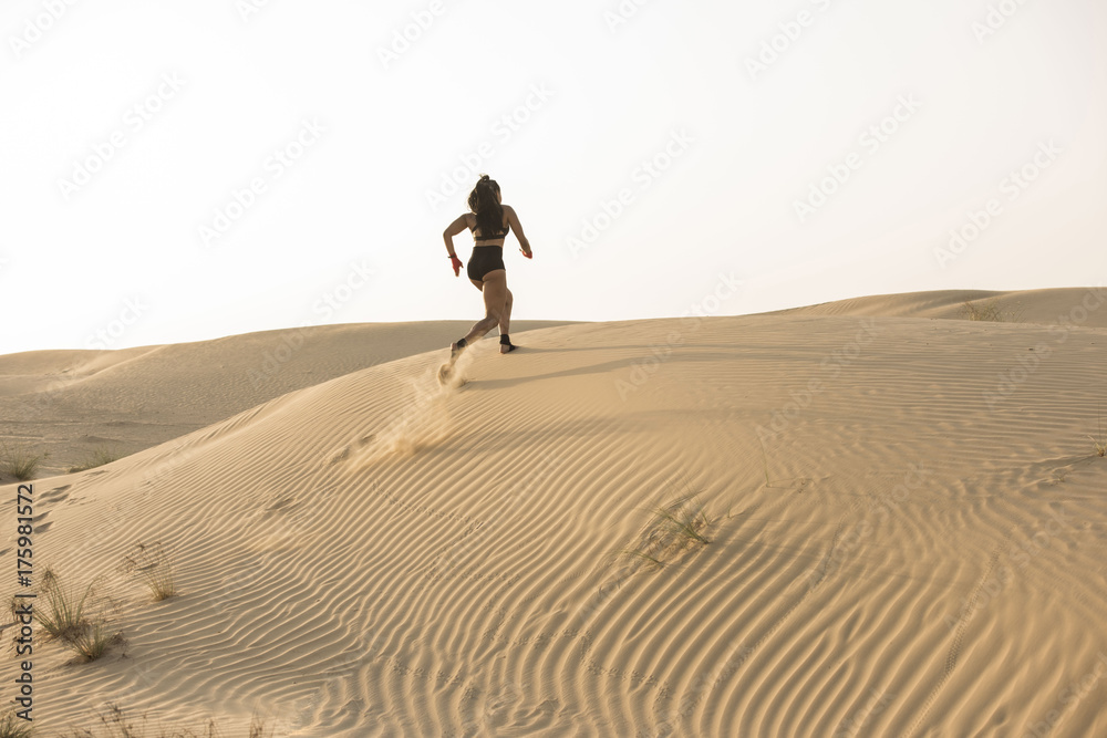 A Beautiful Asian-Black, Mixed Race martial artist female jogging or running with  in the desert at sunrise or sunset wearing black short tights and black sports  bra