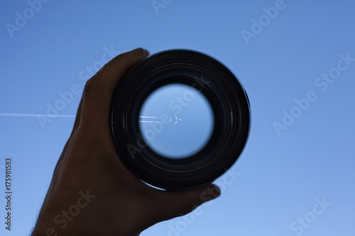View through spyglass lens to the airplane flying in the sky photo