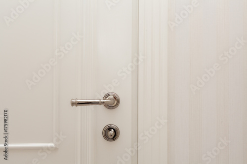 Close white door with metallic handle. © brizmaker