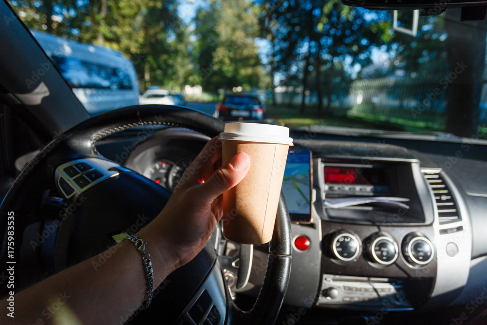The driver is drinking coffee behind the wheel closeup. Transportation, drinks, people and vehicle concept - close up of man drinking coffee while driving car