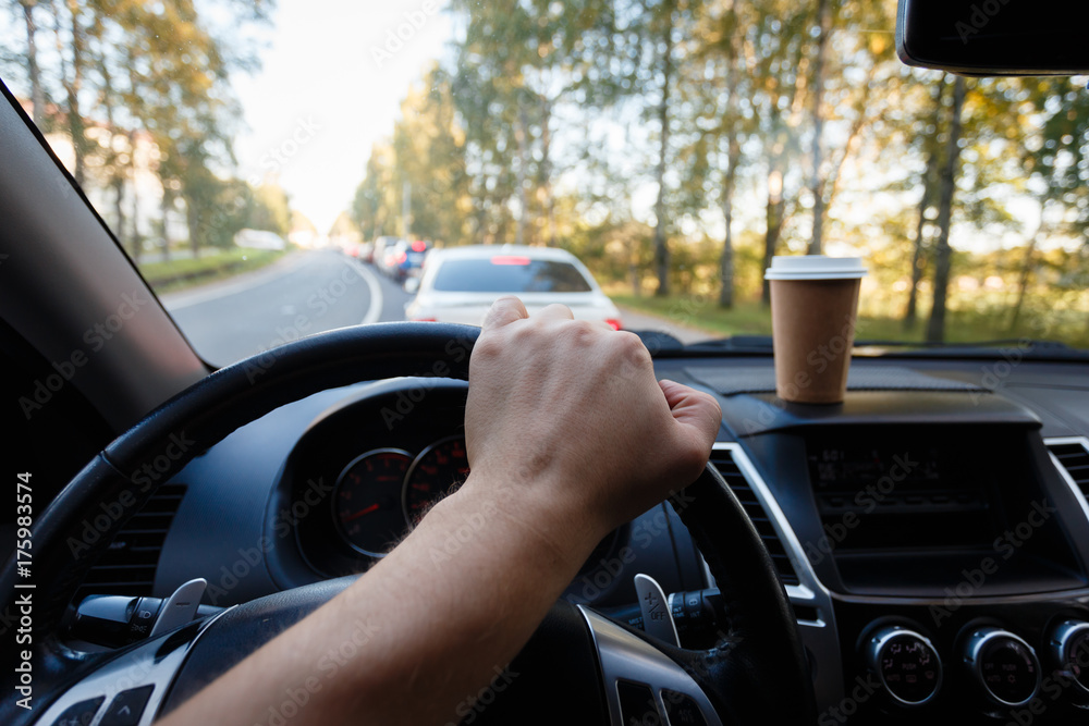 The driver is drinking coffee behind the wheel closeup. Transportation, drinks, people and vehicle concept - close up of man drinking coffee while driving car The driver is drinking coffee behind the wheel closeup. Transportation, drinks, people and vehicle concept - close up of man drinking coffee while driving car