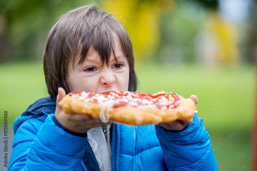 Young preschool child, boy, eating salty bread with cheese and ketchup in the park Young preschool child, boy, eating salty bread with cheese and ketchup in the park