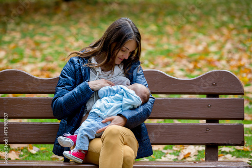 Young mother, breastfeeding her newborn baby boy outdoor in the park