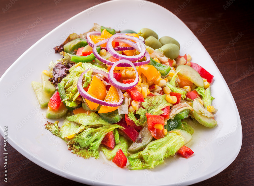Vitamin vegetable salad mix on white plate on dark brown restaurant table Vitamin vegetable salad mix on white plate on dark brown restaurant table