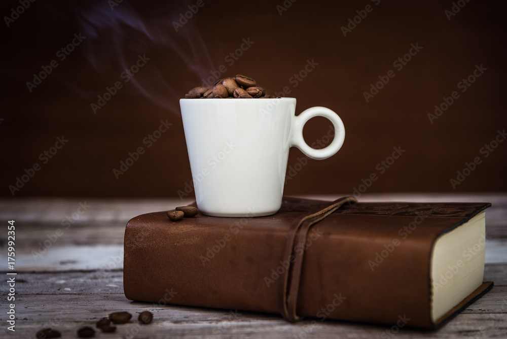 tazza di caffè fumante appoggiata su libro Stock Photo | Adobe Stock