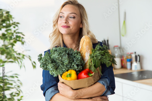 Beautiful young woman grocery shopping bag with vegetables at home.