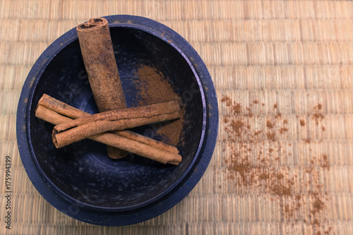 Cinnamon sticks in a wooden bowl on a bamboo mat