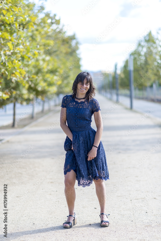 A middle-aged woman is stylishly dressed in a blue dress in a pa A middle-aged woman is stylishly dressed in a blue dress in a pa