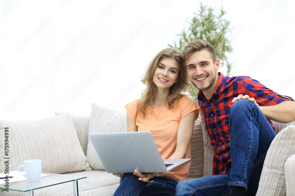 young couple of students with laptop sitting on the couch