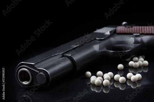 airsoft pistol with bb bullets on black glossy surface