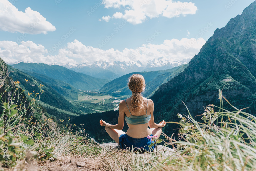 Naklejka premium young girl meditates on a background of mountains