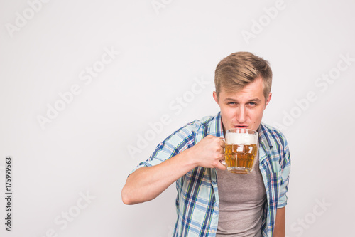 Man drinks beer. Handsome young guy drinking lager pint on white background