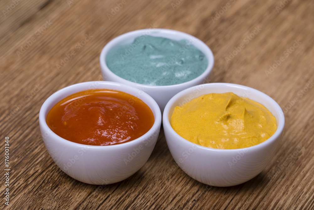 Red tomato sauce, turmeric sauce and spirulina sauce on the wooden background Red tomato sauce, turmeric sauce and spirulina sauce on the wooden background
