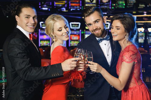 Billede på lærred Group of happy people drinking sparkling wine in the casino