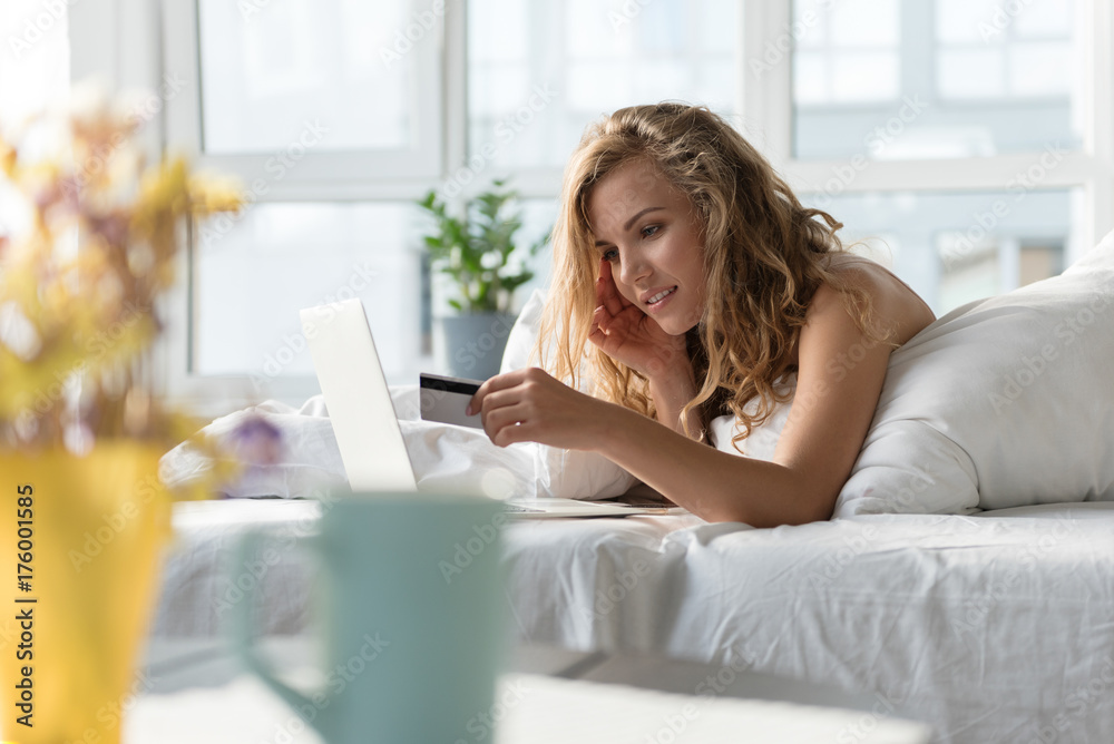 Cheerful smiling girl using gadget in bedding Cheerful smiling girl using gadget in bedding