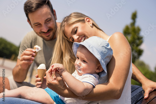 Happy young family eating ice cream and having fun outside