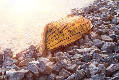 Old wooden boat lying on stones closeup