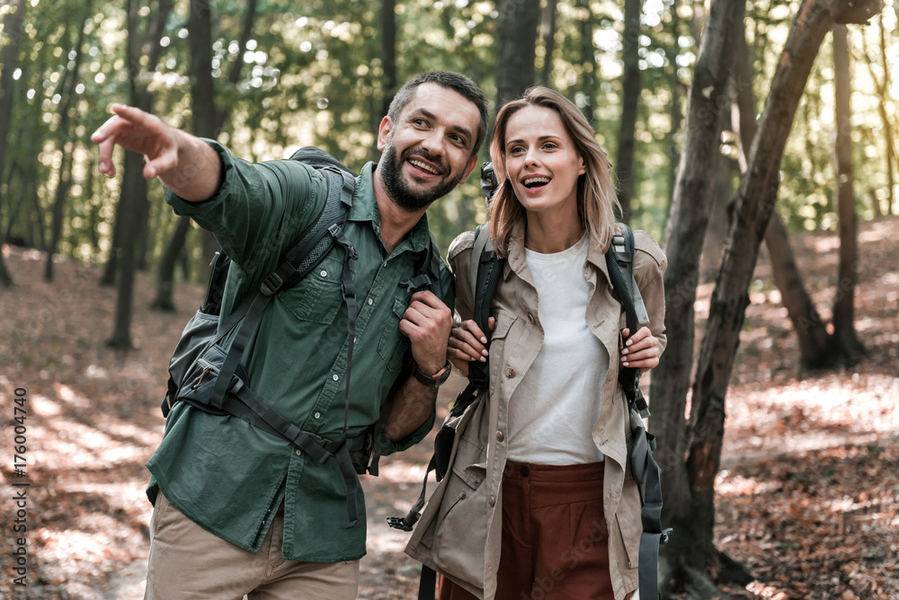 Cheerful male showing way to girl is forest