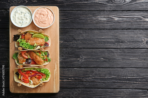 Photography Stand with delicious fish tacos and sauces on wooden background