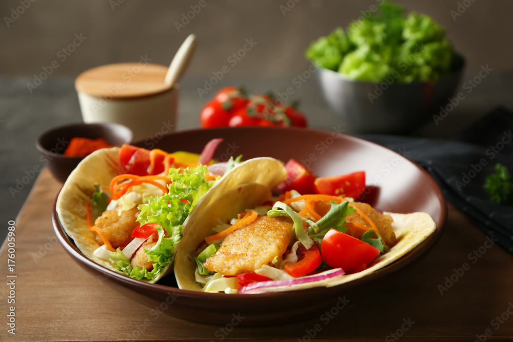 Plate with delicious fish tacos on table