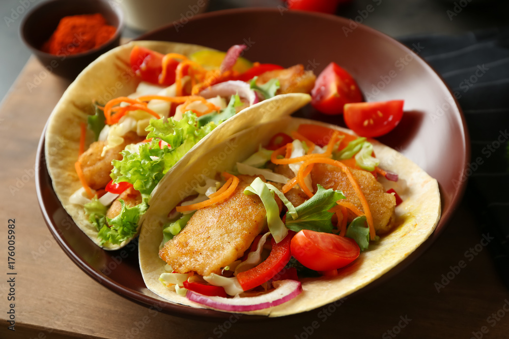 Plate with delicious fish tacos on table