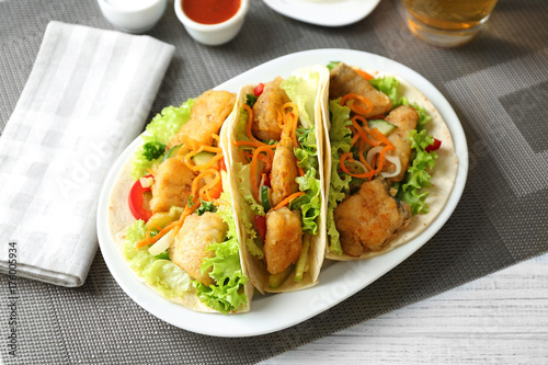 Plate with delicious fish tacos on table