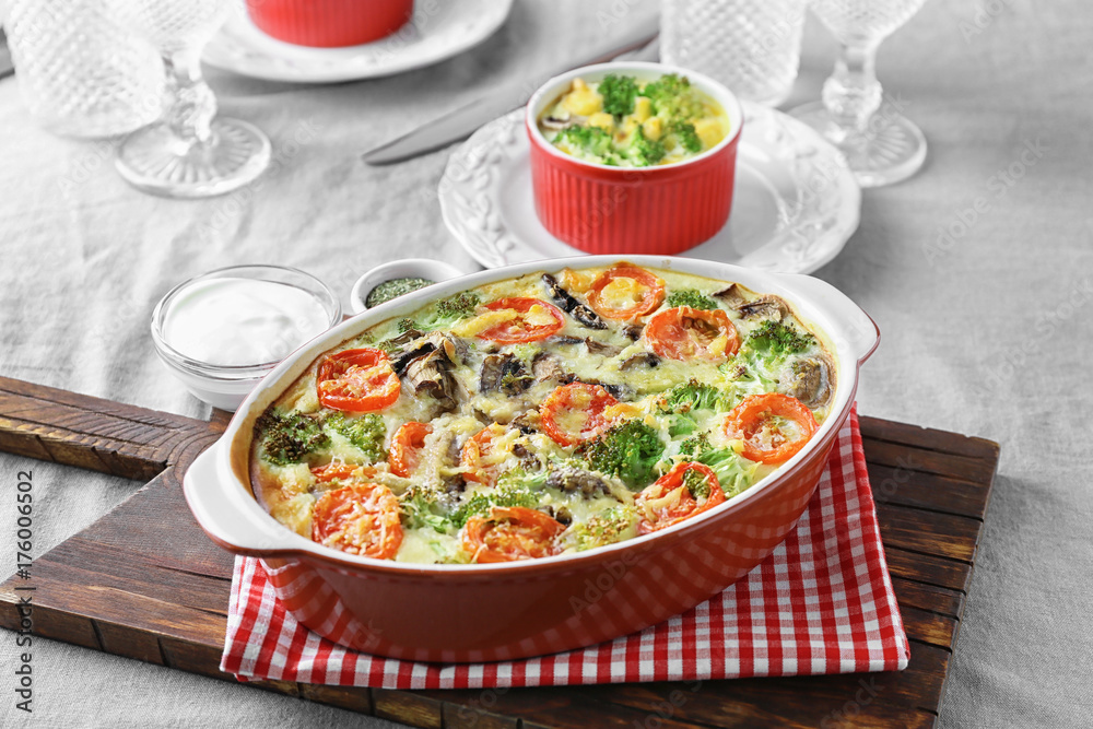 Baking dish with tasty broccoli casserole on table