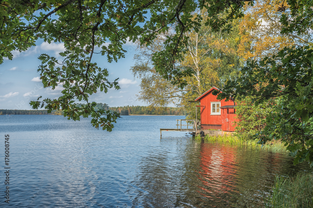 Obraz premium Picture of red wooden scandinavian style house at the lake during autumn