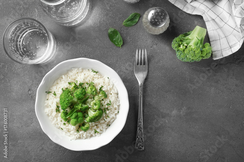 Bowl with rice and broccoli on table