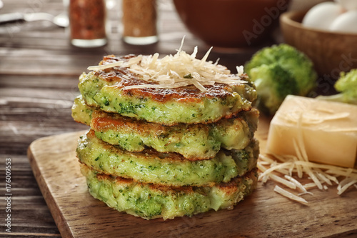 Wooden board with delicious broccoli pancakes on table  close up