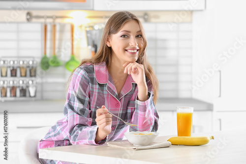 Morning of young beautiful woman having breakfast in kitchen