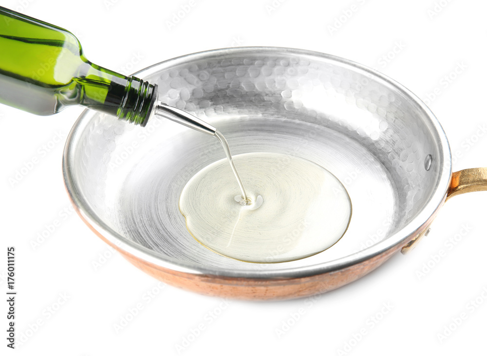 Pouring oil into frying pan on white background Pouring oil into frying pan on white background