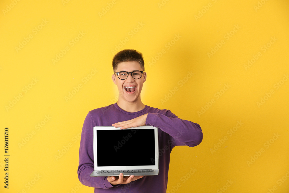 Φωτογραφία Teenager boy with laptop on color background