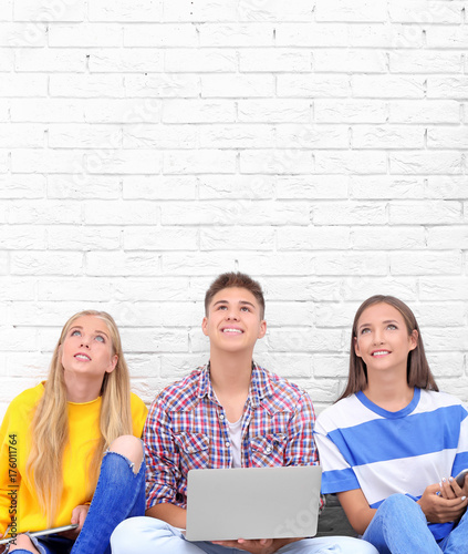 Teenagers with gadgets sitt...