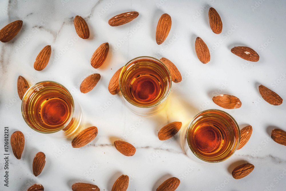 Golden almond liqueur with nuts on white marble background. top view copy space Golden almond liqueur with nuts on white marble background. top view copy space