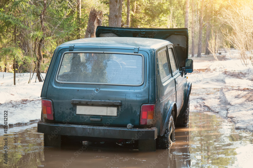 Off-road car stalled in a puddle in the winter forest Off-road car stalled in a puddle in the winter forest