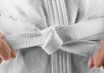 Ingelijste posters Vechtsport Karateka knoopt witte band vast  © Africa Studio