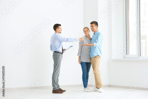 Real estate broker giving customers key from new flat © Africa Studio