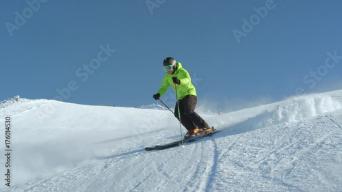 TRACKING SLOW MOTION Amateur skier enjoys idyllic perfect weather on a winter day for recreation skiing down the fresh groomed piste. Modern large ski resort located in Slovenia, Alps, Europe.
