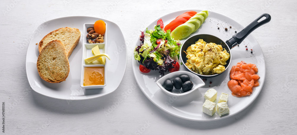 English breakfast. Fried eggs, salmon, olives, nuts, vegetables and dried fruit. Top view. Free space for text. On a wooden background. English breakfast. Fried eggs, salmon, olives, nuts, vegetables and dried fruit. Top view. Free space for text. On a wooden background.