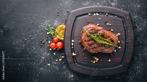 Veal steak with spices on the board. Top view. Free space for text. On a wooden background.