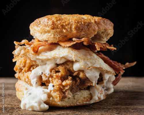 Buttermilk biscuit and fried chicken breast sandwich with a fried egg and bacon