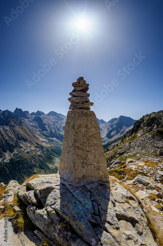 stone column on the top of a mountain path in Maritime Alps Park, Italy, with the shining sun over it